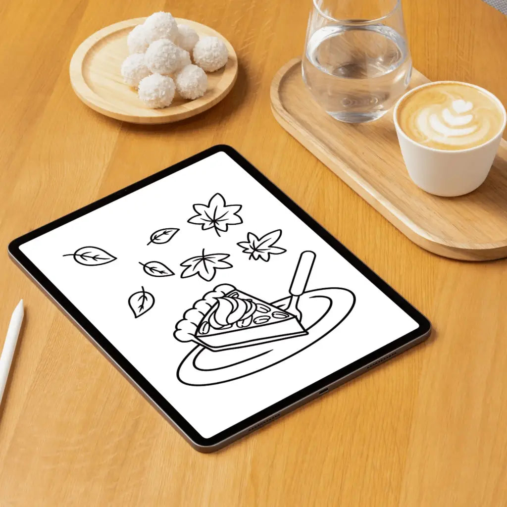 Tablet showing a coloring page of a slice of pecan pie with falling leaves above, sitting on a wooden table with a cup of coffee and a stylus
