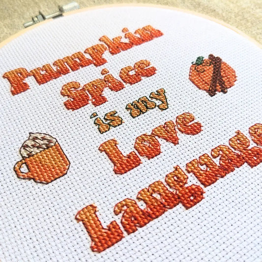 Embroidery hoop with cross-stitched text and illustrations on a white background