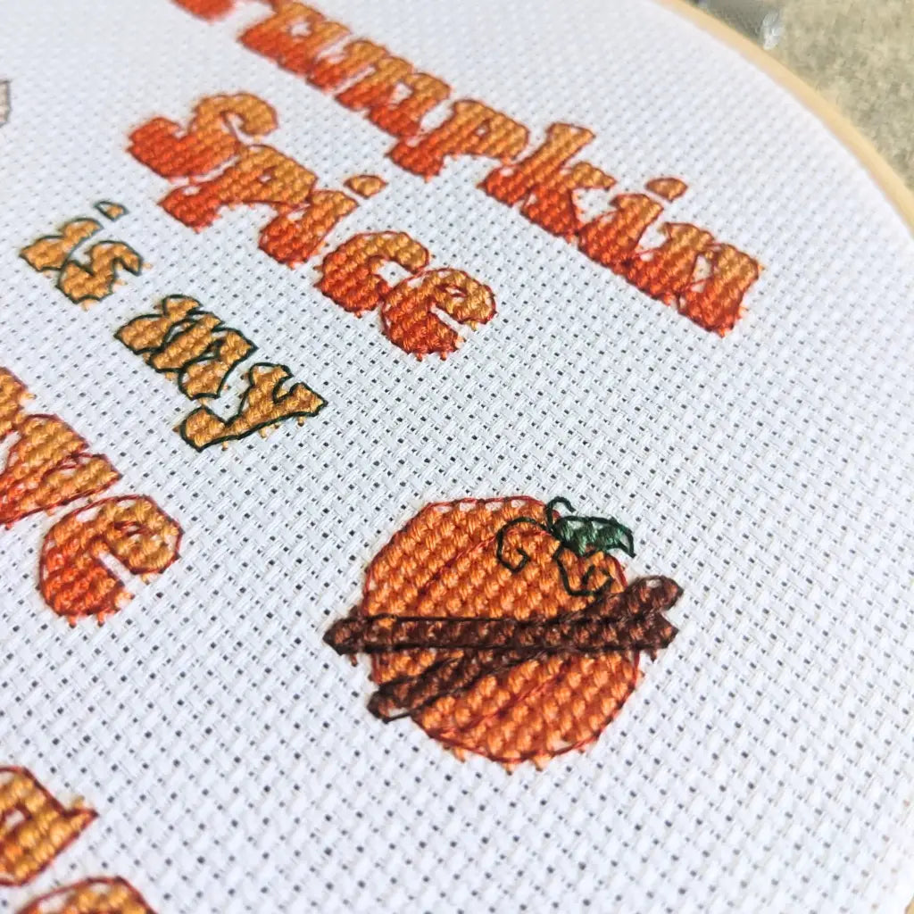 Close up of a cross stitched pumpkin with cinnamon sticks, a motif on the pumpkin spice lover cross stitch pattern by Room for Calm