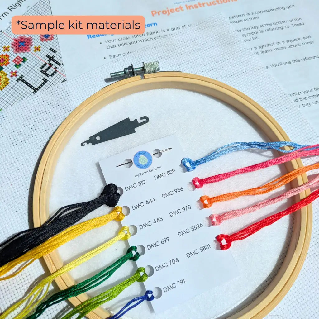 Embroidery hoop with colorful threads and a cross-stitch pattern on paper