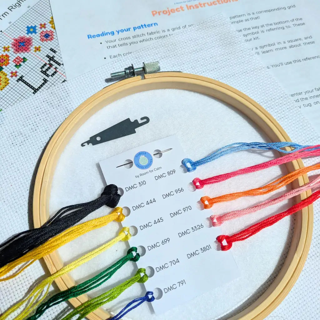 Embroidery hoop with colorful threads and cross-stitch pattern on paper
