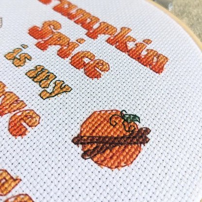 Close up of a cross stitched pumpkin with cinnamon sticks, a motif  on the pumpkin spice lover cross stitch pattern by Room for Calm